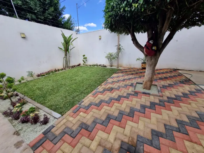 Patio con adoquín en patrón de espiga junto a un jardín