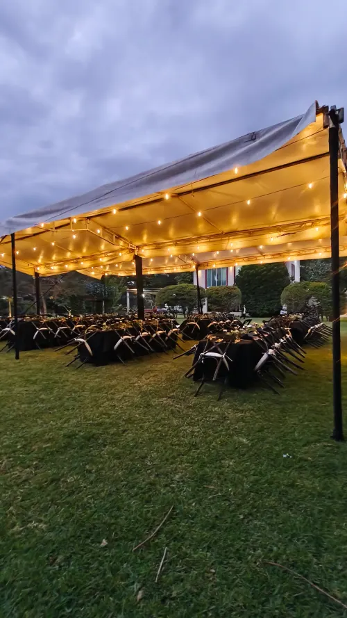 Carpa con mesas, sillas y luces montada en el jardín de Los Leones para un evento