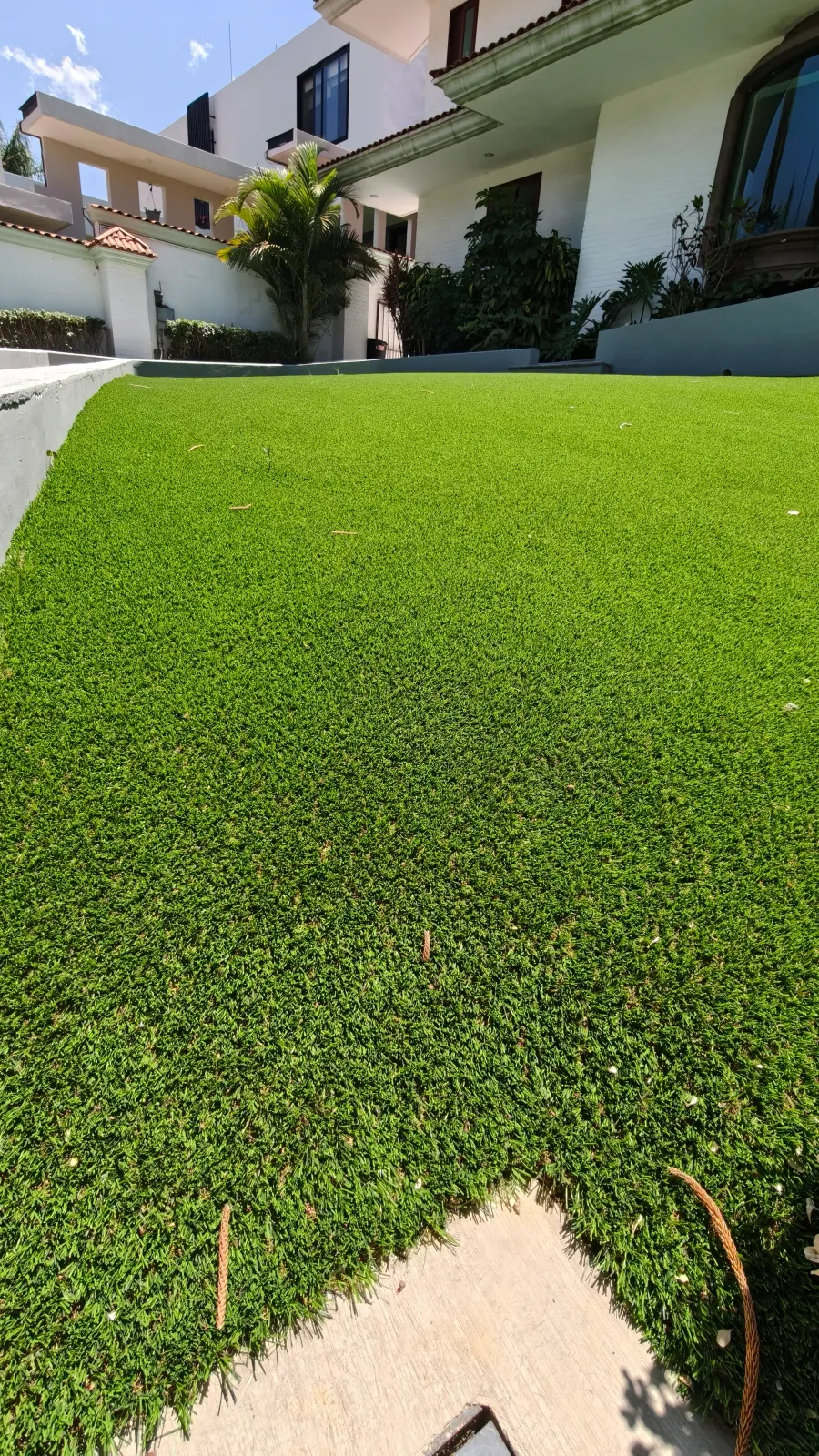 Jardín frontal amplio de pasto sintético frente a una casa moderna